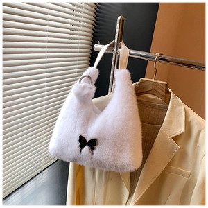 Detail of plush white faux fur handbag featuring black butterfly motif and jeweled rings