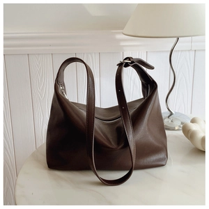 Detail of dark brown leather hobo bag with smooth texture on white marble table