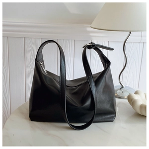 Detail of adjustable silver buckle strap and matte leather texture on black tote bag