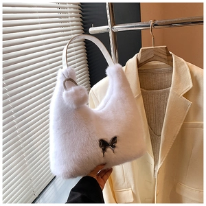 Close-up of white faux fur handbag featuring a butterfly metal buckle and pompom charm