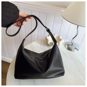 Close-up of black matte leather Hobo bag with silver zipper on marble table surface