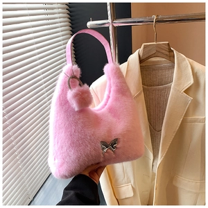 Detail view of pink plush crescent bag with silver butterfly charm and soft pompom accessory