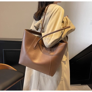 Detailed view of brown tote bag side stitching and premium leather texture on model