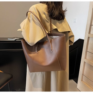 Detail of a large brown tote bag showing smooth faux leather texture and sturdy straps