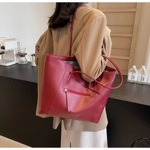 Detail of red oversized tote bag with lychee texture and practical front zipper pocket