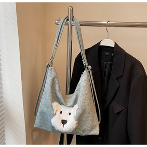 Detail of grey knitted tote bag featuring a 3D plush white dog head patchwork design