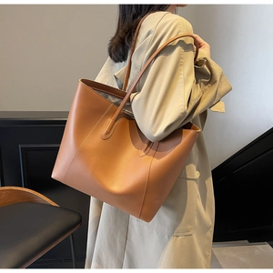 Detail of classic caramel brown tote bag with premium stitching worn over a trench coat