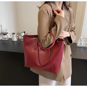 Close-up of a large red leather tote bag with round handles for daily commuting style