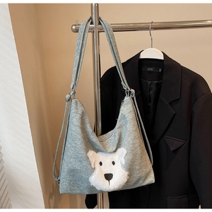 Detail of grey knitted tote bag featuring a cute white plush puppy patch on the front surface
