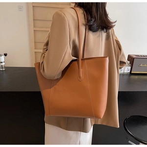 Detailed view of brown leather tote bag with fine stitching in a cafe setting
