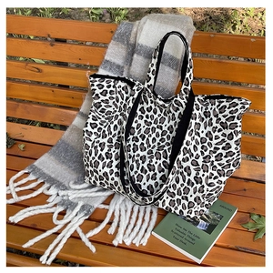 Detailed close-up of leopard print canvas tote bag on a wooden bench with autumn accessories