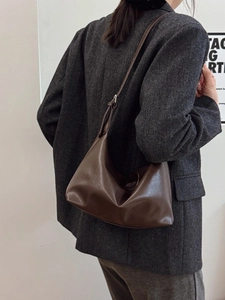 Deep brown leather tote bag worn as a shoulder bag in a minimalist lifestyle setting