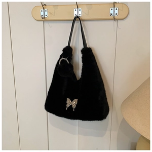 Detail of black faux fur shoulder bag with silver butterfly metal piece and pompom