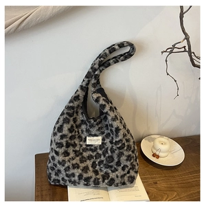 Gros plan d'un sac seau en peluche léopard avec étiquette sur un bureau en bois
