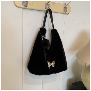 Close-up of black faux fur tote bag featuring a silver butterfly buckle and plush pompom charm