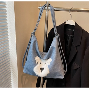 Detail of blue denim tote bag featuring a cute white plush dog patch on the front