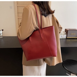 Detail of burgundy leather tote bag with vertical stitching in a cozy cafe setting