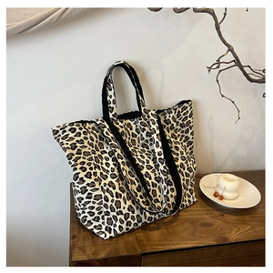Close-up of leopard print canvas tote bag on wooden table with decorative accents