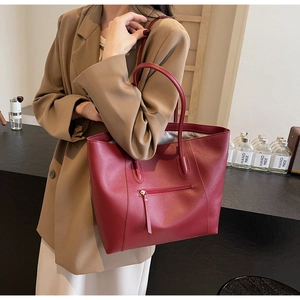 Detail of red lychee textured leather tote bag featuring a practical front zipper pocket