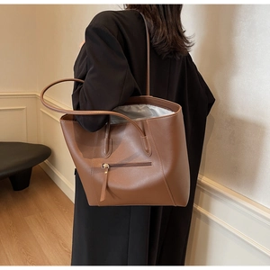 Close-up of caramel brown large tote bag with zipper detail and slim shoulder straps