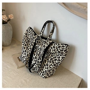 Close-up of leopard print canvas tote bag with durable black woven straps in a lifestyle setting