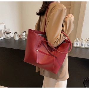 Detail of burgundy leather tote bag with functional zipper pocket and long handles