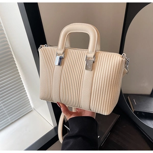 Detail of cream white bucket bag with vertical stripe texture and silver metal hardware