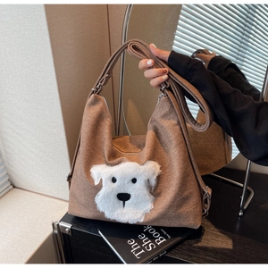Detail of brown canvas hobo bag featuring a plush 3D dog head patch and wide shoulder strap