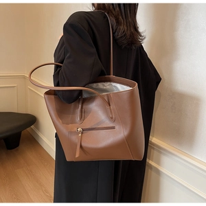 Detail view of the deep brown large tote bag featuring a front zipper pocket and matte leather