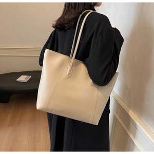 Detail view of cream leather tote bag featuring fine stitching and minimalist handles