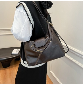 Detail view of dark brown leather tote with Muon Shark logo and gold hardware