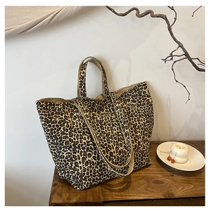 Detailed macro shot of leopard print canvas tote bag with dual handles and long shoulder strap