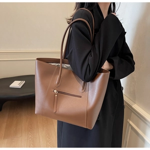 Detailed view of brown leather tote bag with front zipper pocket and clean stitching
