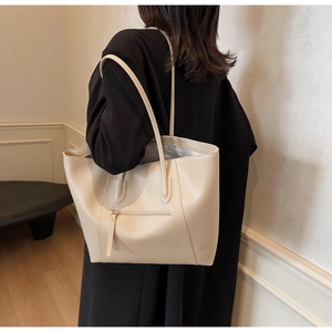 Detailed side view of beige leather tote bag with long strap worn on shoulder