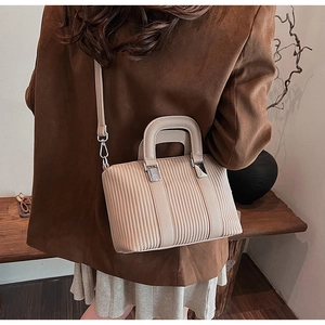 Detailed view of beige vertical quilted bucket bag with silver hardware and shoulder strap