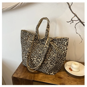 Close-up of leopard print canvas tote bag with dual handles on a wooden surface