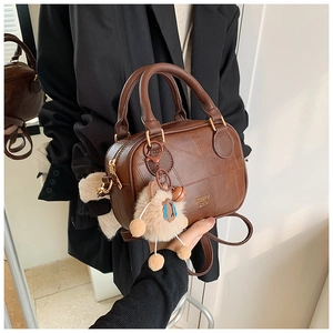 Detail view of brown vintage PU leather handbag with stitching and plush sheep charm