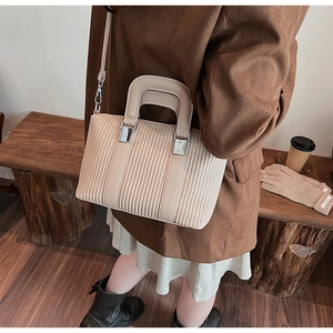 Détail de la texture plissée verticale et de l'anse en cuir de ce sac à bandoulière beige