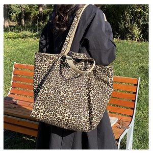 Detailed close-up of a leopard print canvas tote bag worn on shoulder in outdoor setting