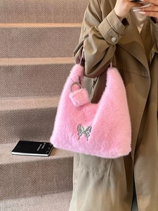 Pink plush tote bag with silver butterfly emblem and fuzzy charm detail shown on stairs