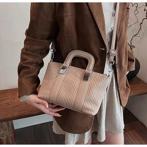 Detail of beige bucket bag with vertical pleated texture and silver buckle accents