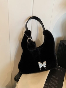Furry black tote bag with silver butterfly buckle and plush ball charm in a stylish setup