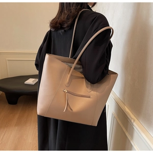 Detail of apricot matte leather tote bag featuring a front zipper pocket and long straps