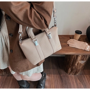 Detail of beige pleated tote bag featuring silver buckle and chic autumn style