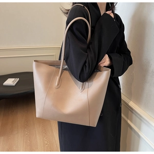 Detailed view of nude pink leather tote bag texture and slim shoulder strap on black coat