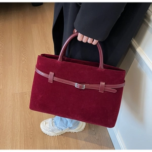 Detail of burgundy suede tote bag featuring silver buckles and sturdy round handles