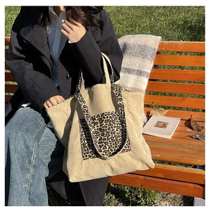 Detail of leopard print corduroy tote bag featuring a textured front pocket and soft strap