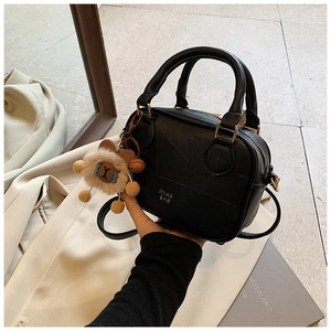 Detail of black PU leather crossbody bag featuring a plush charm and brand lettering