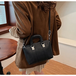 Model wearing a vintage black pebbled leather bucket bag in a warm indoor setting