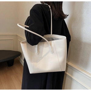 Detailed view of spacious interior and matte leather finish on a white tote bag